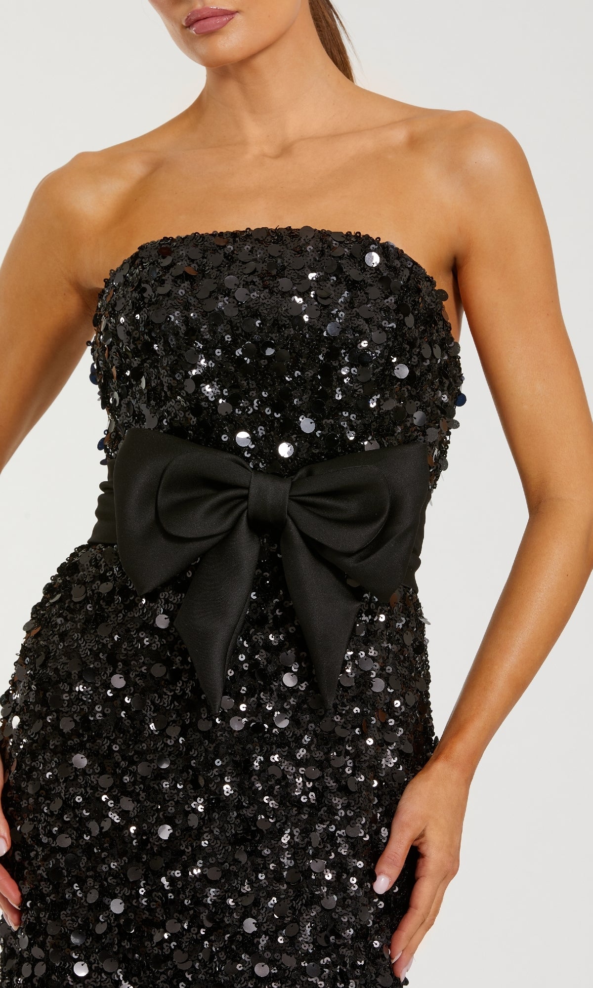 Black sequin strapless dress with a large bow on a white background